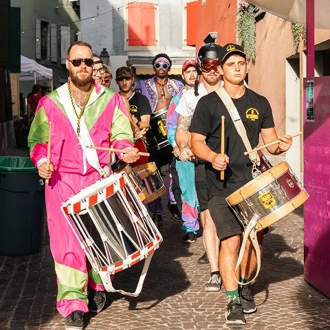 Fanfare en costumes colorés anime la Braderie d’Aigle 2025 avec des percussions festives